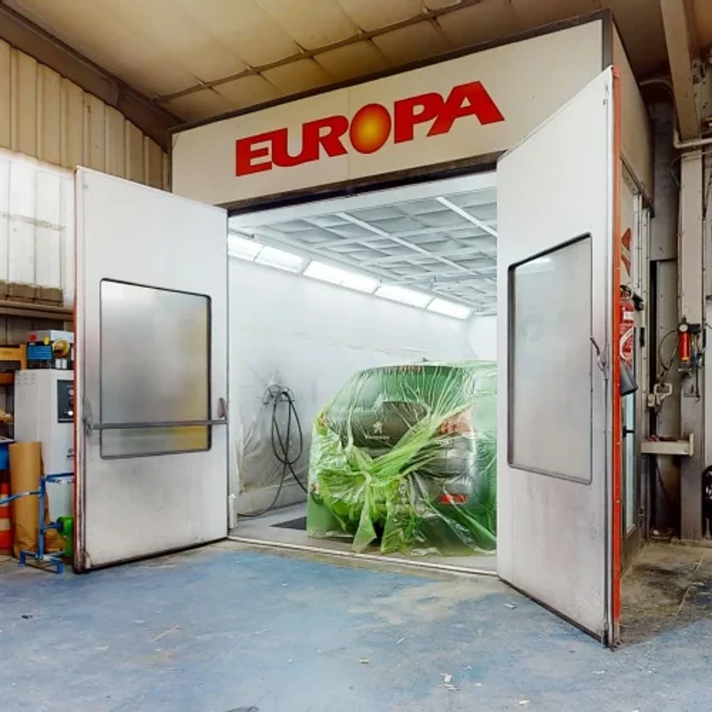Cabine de peinture automobile Europa avec une voiture protégée par un film plastique.