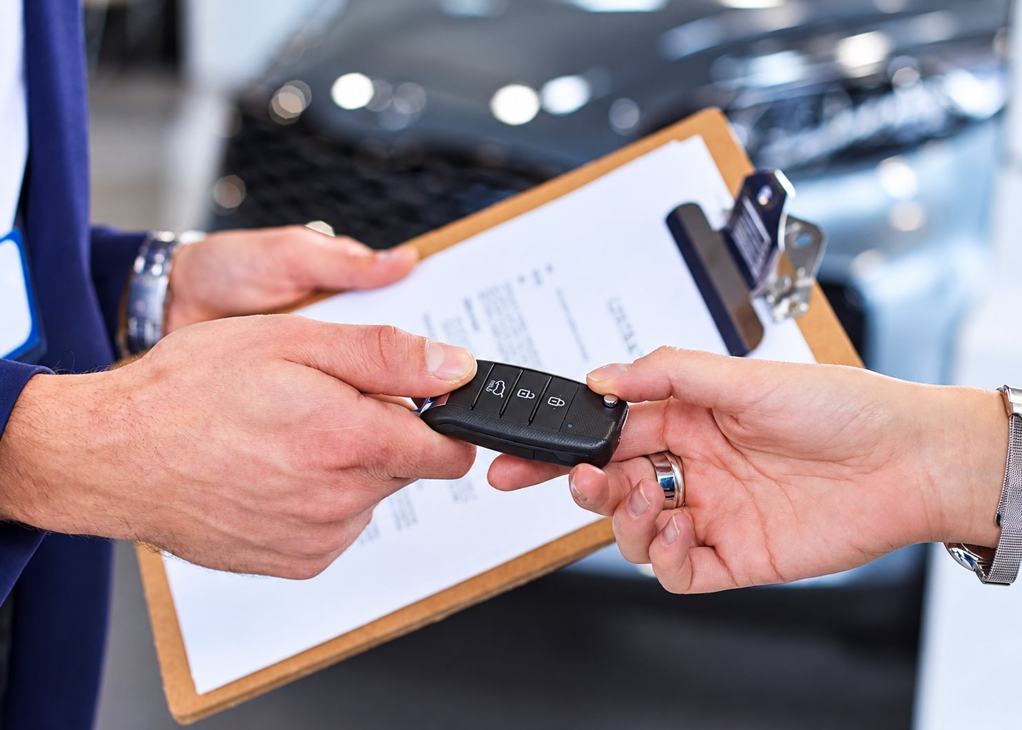 Remise des clés d’une voiture par un vendeur, avec un presse-papiers à signer.