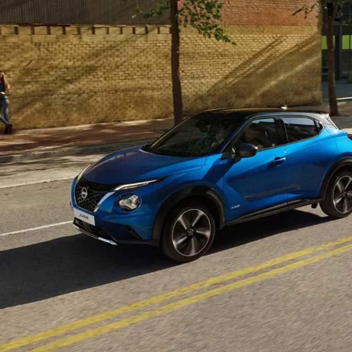 Un SUV compact bleu Nissan Juke dans une rue ensoleillée.